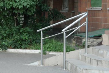 Caddedeki binanın girişindeki gri merdivenlerde beyaz metal trabzanlar var.