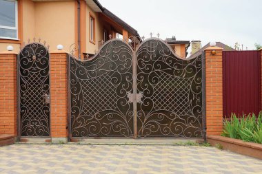 Dövme desenli kahverengi metal kapı ve caddede kırmızı bir çit var. 