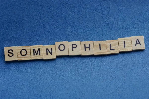 青い背景に黒いフォントの小さな正方形の木製の文字で灰色の単語Somnophyia — ストック写真