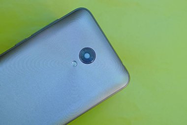 Sarı arkaplandaki gri metal akıllı telefonun parçası.