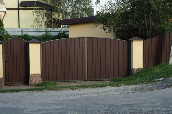 一个棕色大门和城墙上的金属围栏的一部分 位于城市街道上 — 图库照片