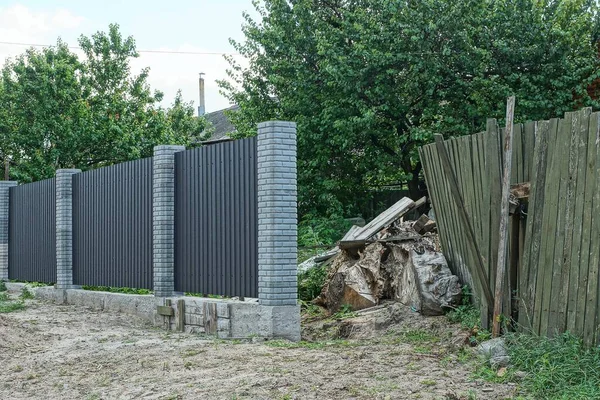 part of old broken wooden fence and unfinished gray brick and metal wall in the street