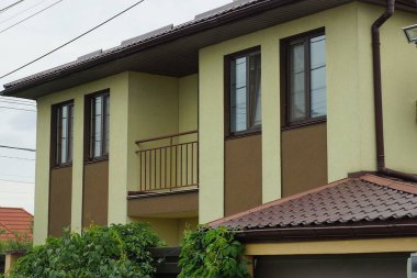 Pencereli özel bir evin ön cephesinde açık kahverengi bir balkon.