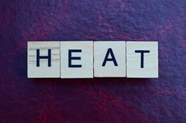 Kırmızı masa üzerinde siyah yazı tipi olan gri ahşap harflerden ısı kelimesine mesaj at.