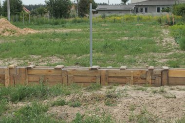 Dışarıdaki yeşil çimenlikteki çitin temeli üzerine ahşap tahtalardan yapılmış uzun kahverengi bir yapı.