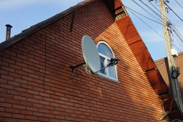 白い小さな窓のある赤レンガの家の屋根裏部屋と衛星料理 — ストック写真