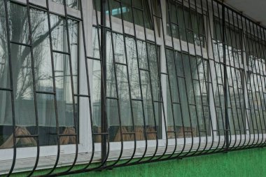 Dışarıda yeşil bir duvarda siyah demir parmaklıklar olan beyaz pencere.