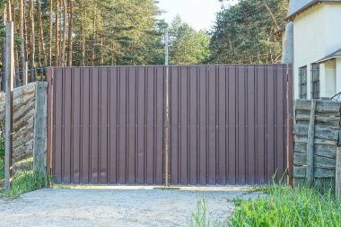 bir kapalı kahverengi metal kapı ve yeşil çimlerin üzerinde çitin bir kısmı