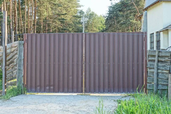 bir kapalı kahverengi metal kapı ve yeşil çimlerin üzerinde çitin bir kısmı