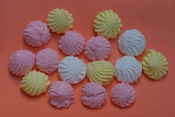 food from round colored marshmallow candies lie on a pink table