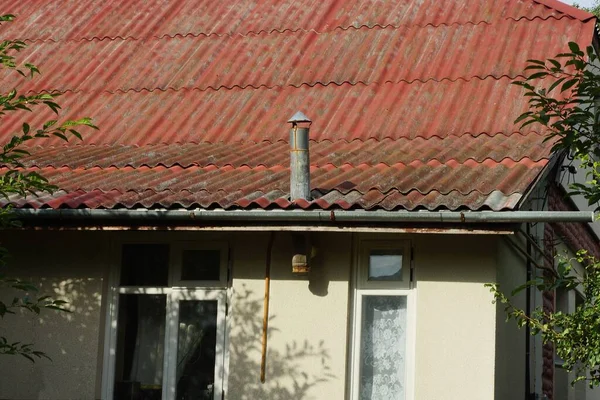 Özel bir evin kırmızı tahta çatısında gri metal baca.