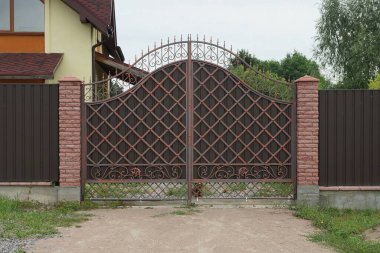 Kahverengi metal kapılı, sahte desenli ve sokakta bir parça tuğla çitli.