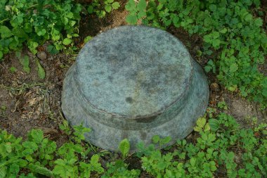 Eski bir gri bakır leğen doğanın yeşil çimlerinde yatar.