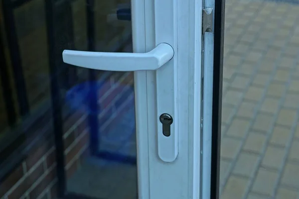 one white plastic door handle on a glass door outside