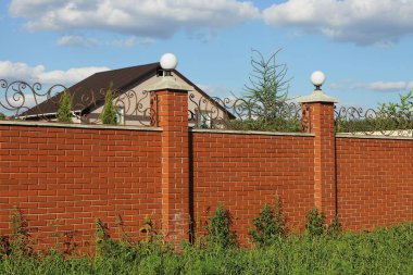 Gökyüzüne karşı yeşil çimlerde beyaz fenerlerle çevrili kırmızı tuğlalar.