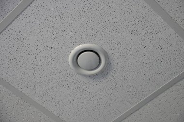 Beyaz yuvarlak plastik alarm odadaki gri tavanda.