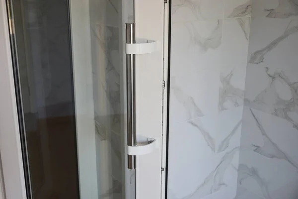 gray metal door handle on white plastic and glass door in the room