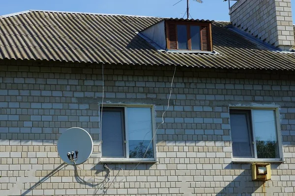 Dwa Okna Antena Satelitarna Szarej Ceglanej Ścianie Domu Pod Dachem — Zdjęcie stockowe
