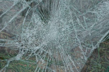 Eski gri bir cam parçasının deseni. Sokakta çimlerin üzerinde çatlaklar var.