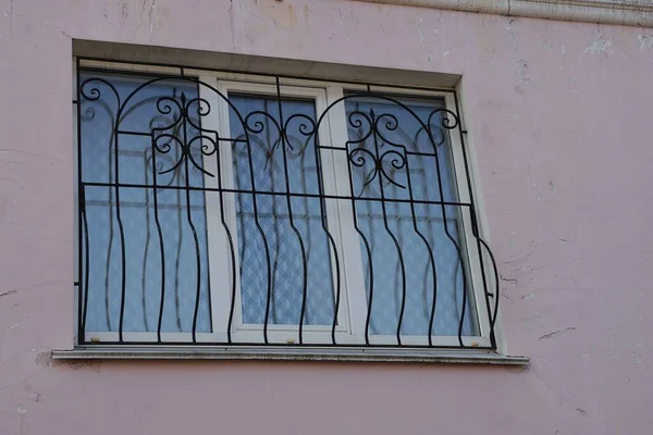 Jedno Białe Okno Czarnymi Prętami Żelaza Różowej Ścianie Pęknięciami Ulicy — Zdjęcie stockowe