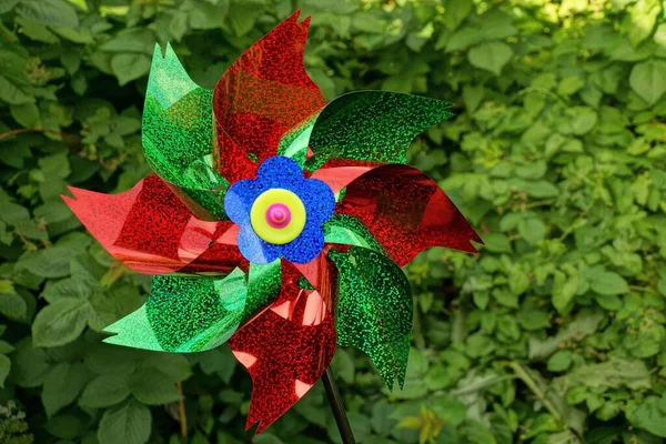 Doğadaki yeşil bitki örtüsünün arka planında büyük renkli bir plastik oyuncak yel değirmeni.