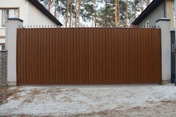 Kırsal bir sokakta büyük, kahverengi, kapalı bir demir kapı.