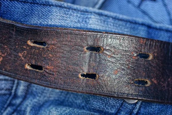 ジーンズのズボンの青い綿の生地の茶色の革ベルトの一部 — ストック写真