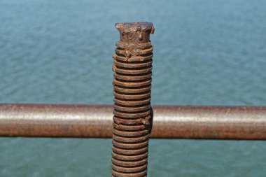 Pas içinde eski kahverengi uzun demir bir iğne. Mavi arka planda iplik var.