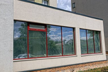 Güneşli bir günde büyük pencereli bir evin gri beton duvarı