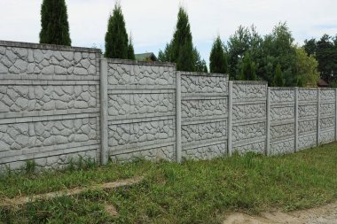 Kırsal bir sokakta uzun, beton bir çit.