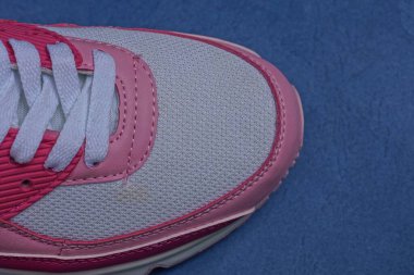  Beyaz kumaştan ve kırmızı deriden yapılmış bir spor ayakkabısının parçası mavi bir masada duruyor.