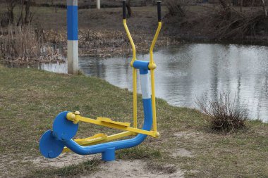 bir renkli demir spor durağan bisiklet yerde ve yeşil çimlerin içinde su deposunun kıyısında duruyor.