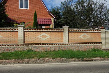 Kahverengi uzun tuğla ve taştan çitler Sokakta yeşil çimlerde