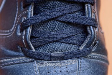 Kahverengi arka planda siyah deri bir çizme.