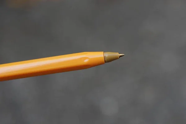 灰色の背景に長いプラスチックのオレンジ色のペンがあり — ストック写真