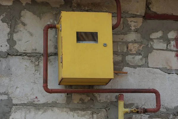 One yellow metal gas meter with brown iron pipe on gray concrete wall outside — Stock Image One Yellow Metal Gas Meter Brown Iron Pipe Gray Concrete Royalty Free Stock Photos