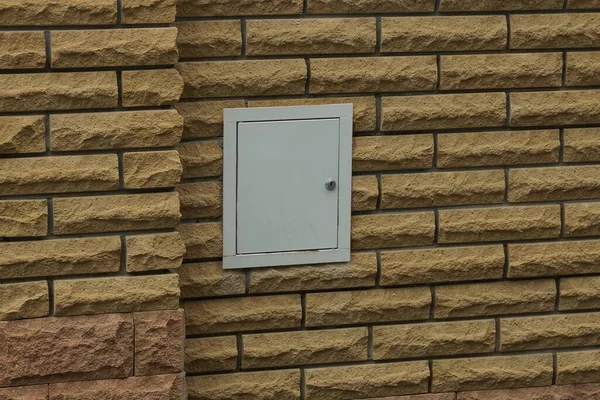 室外篱笆的褐色砖墙中的电线用灰色金属盒 — 图库照片