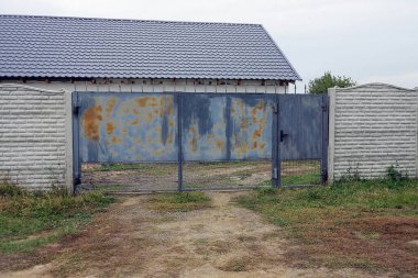 Kahverengi paslı mavi eski demir kapı ve sokaktaki gri beton çitin bir kısmı