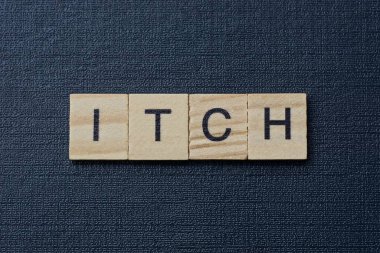 Gri kelime, siyah bir masanın üzerindeki küçük tahta harflerden kaşındırıyor.