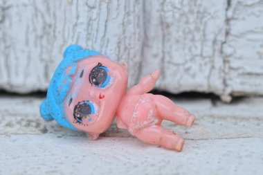 Küçük pembe bir oyuncak bebek yaz caddesinde beyaz bir masada yatıyor.