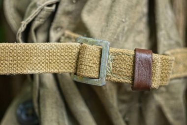 Eski bir ordu sırt çantasında gri metal karabina ile yeşil kumaş koşumu.