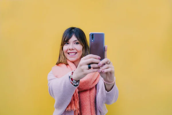 かなりかなり微笑んでいる女の子が彼女の携帯電話で写真を撮る — ストック写真