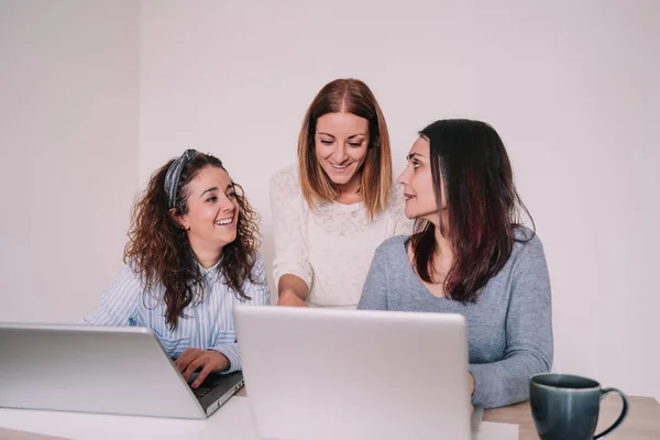 three women are laughing while working together in the office