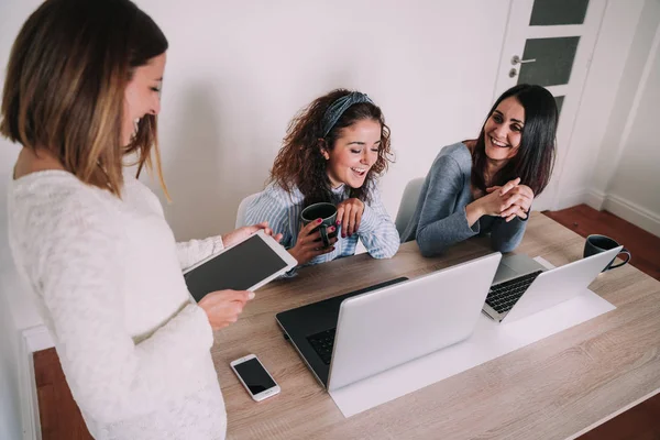 Group of women working in the office while they talk and laugh