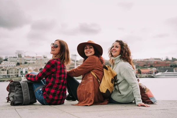 Drie vrienden zitten aan de oever van de rivier in Porto — Stockfoto