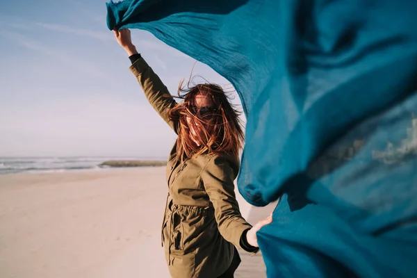 Mooie vrouw waait een sarong op het strand — Stockfoto