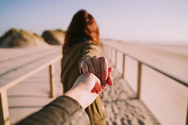 Een persoon die de hand van een vrouw na haar in het strand — Stockfoto