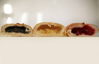 Farklı dolgular ile üç kek içi-haşhaş, elma, kiraz. Doğal güneşli yumuşak aydınlatma ile beyaz bir arka planda. Yazıt alanı ile.