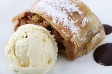vanilyalı dondurma ile elma strudel, beyaz bir arka plan üzerinde beyaz bir tabak üzerinde çikolata ve pudra şekeri ile süslenmiş. Close. 