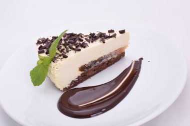 hafif bir arka plan üzerinde izole beyaz bir tabak üzerinde çikolata parçaları ile iştah açıcı cheesecake parçası